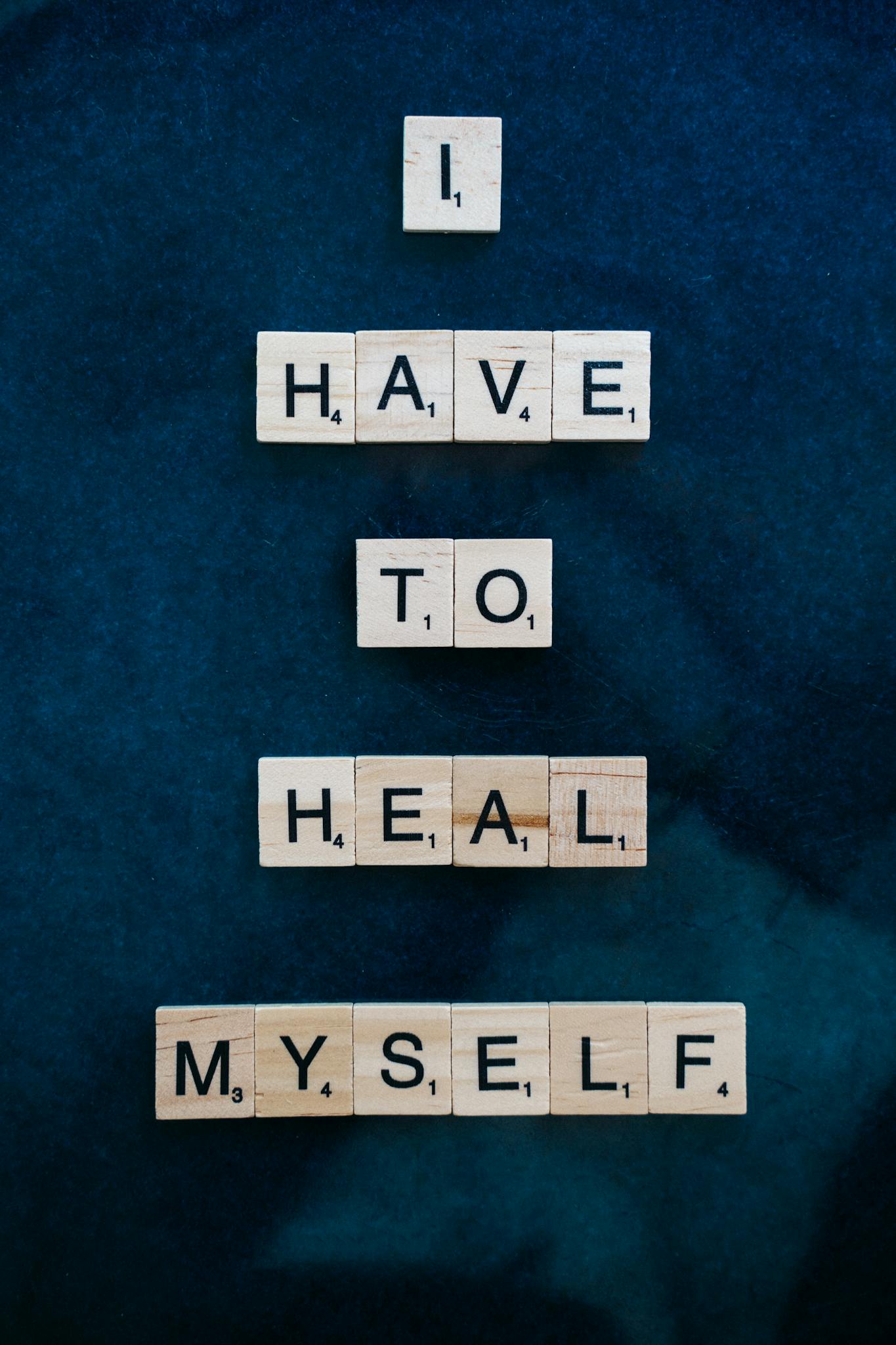 Scrabble tiles forming 'I Have to Heal Myself' on a dark blue backdrop, promoting self-awareness.